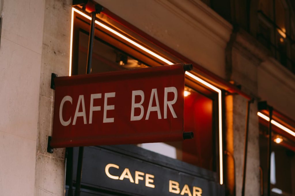 Κόκκινη επιγραφή cafe-bar στην πρόσοψη καταστήματος με ζεστό φωτισμό